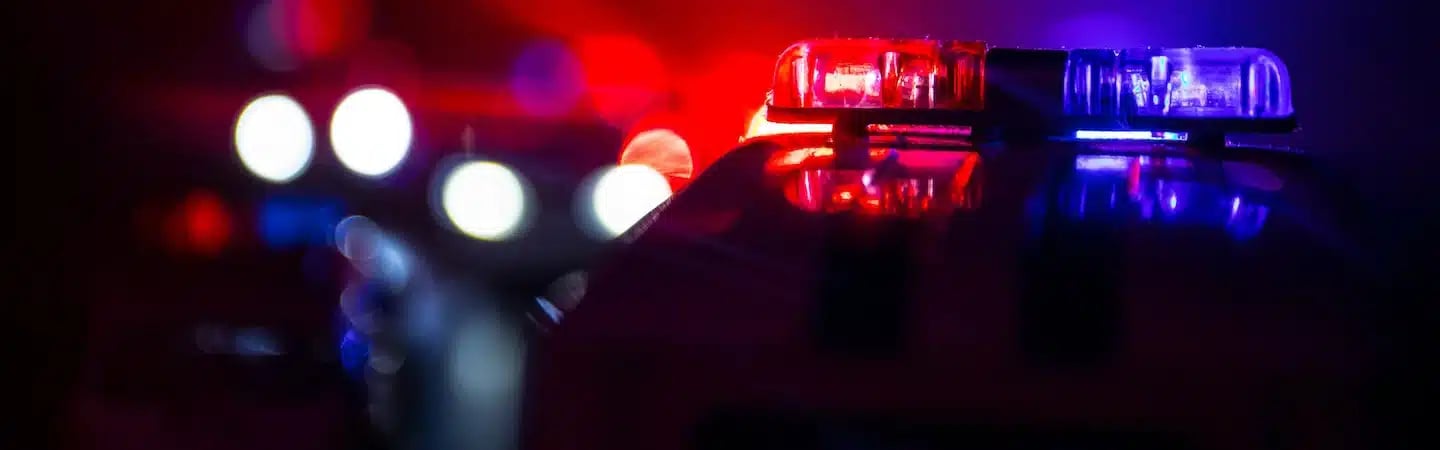 Close-up of emergency vehicle lights flashing red and blue in a dark setting.