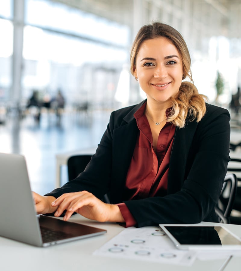 A woman sitting at a desk with a laptop reviews financial data using a Budget Analyst Template.