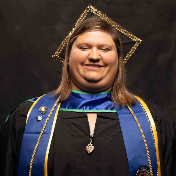 A person wearing a graduation cap and gown with a blue and gold stole.