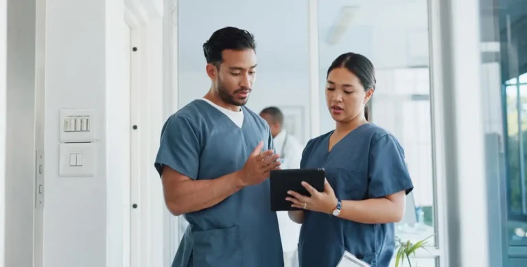 Two healthcare professionals looking at tablet in healthcare environment