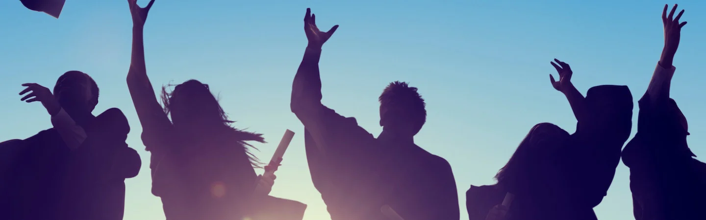 Silhouetted graduates tossing caps and holding diplomas in the air against a clear blue sky.