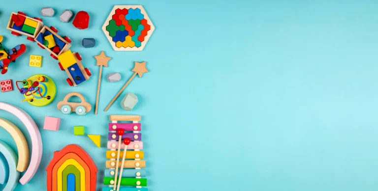 Assorted colorful children's toys arranged on a blue background, including a xylophone, building blocks, and a toy car.