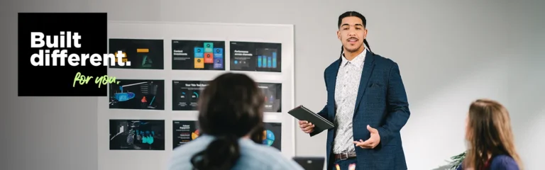 A man in a suit presents charts to colleagues in a meeting room. Text reads, "Built different. for you.