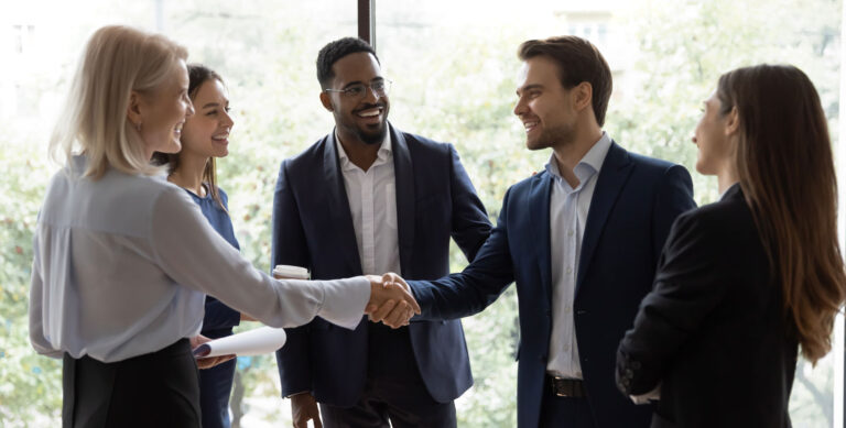 A group of business professionals shaking hands and smiling, symbolizing collaboration and the importance of understanding financial equities in investment and business growth.