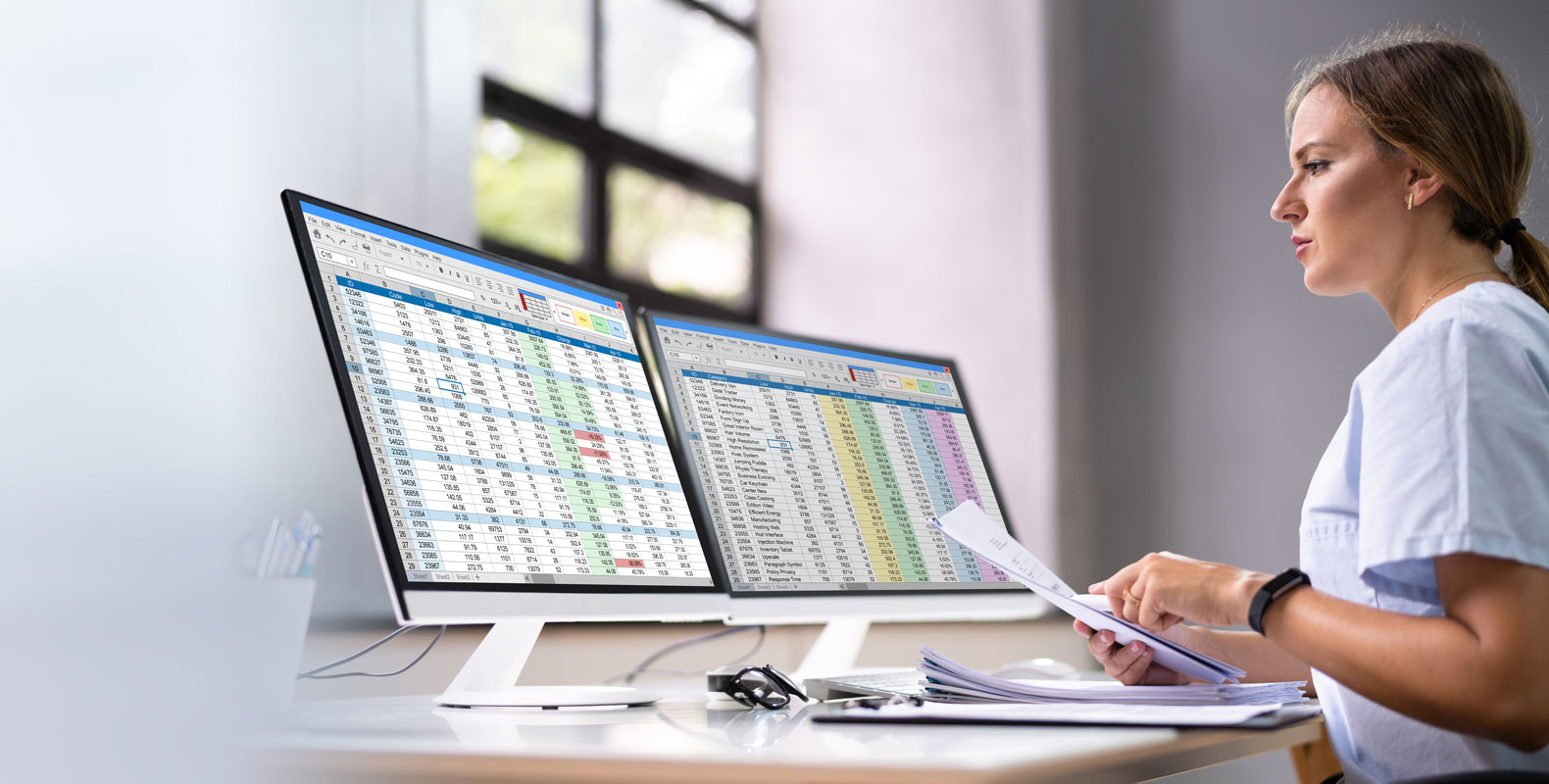 A healthcare worker in scrubs analyzing data on two large monitors, illustrating the use of common CPT codes in medical billing.