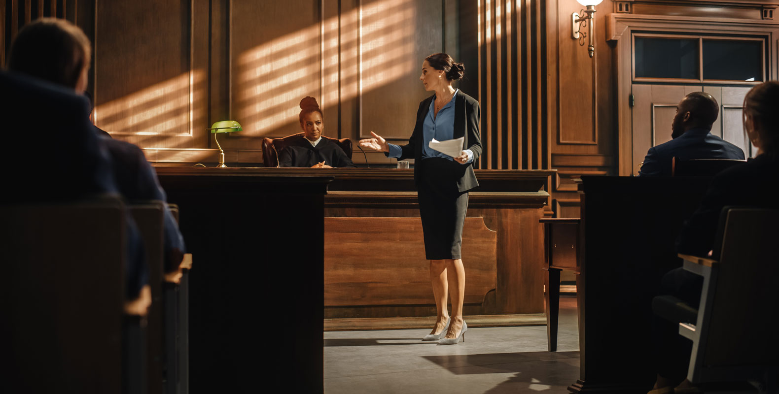 A lawyer presents a case in court, with a judge in the background, representing the differences in roles between paralegals and lawyers.