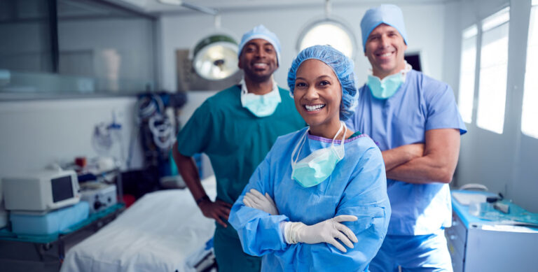 A team of surgeons in scrubs and masks stand confidently in an operating room, representing one of the many environments where nurses work.