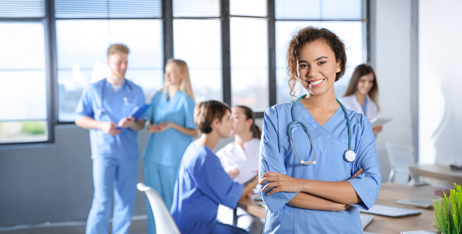 A group of medical students working together, with a female nurse smiling in the foreground.